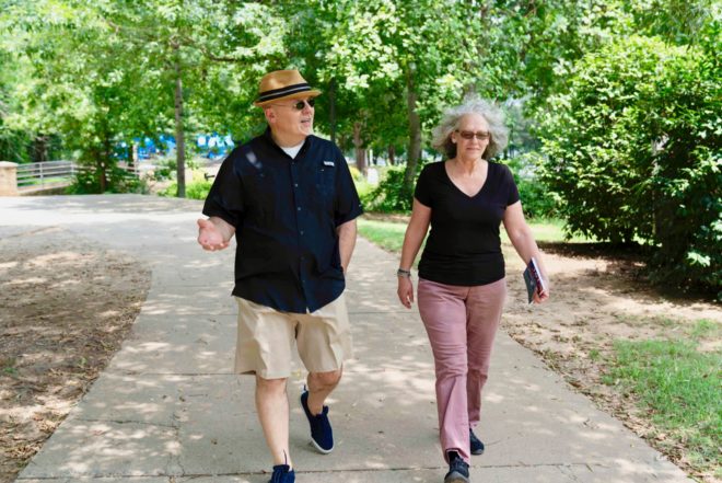 middle aged couple walking along a park path talking